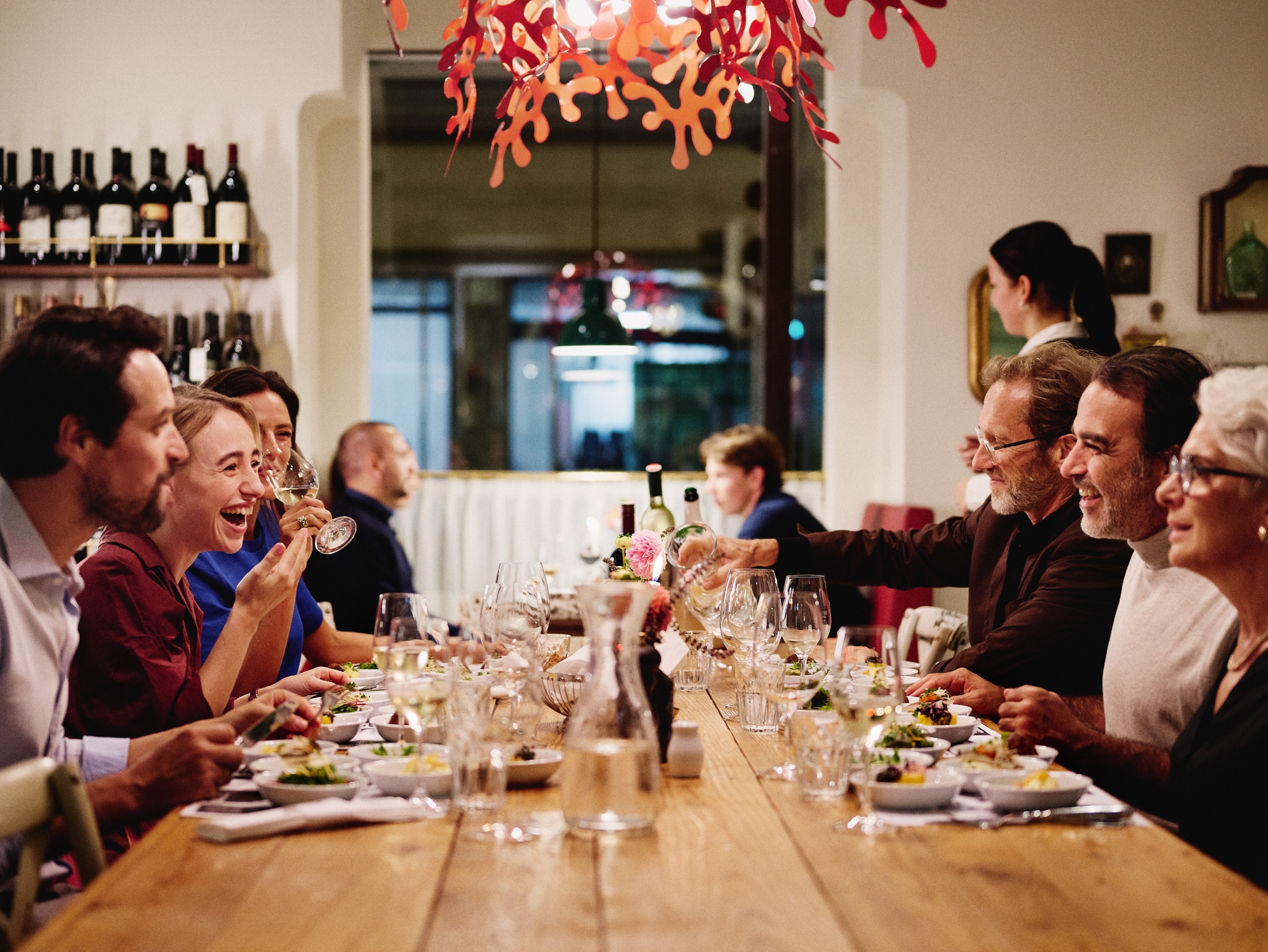 Eine Gruppe von Leuten sitzt an einem Holztisch in einem Restaurant und isst zu Abend.