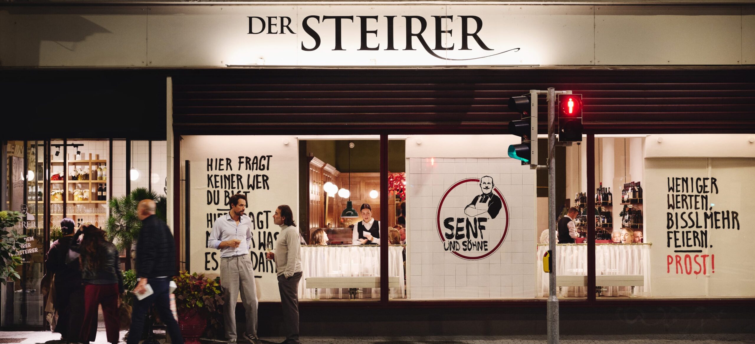 "Der Steirer" Fassade mit "Senf und Söhne"-Logo und Slogans wie "Weniger werten. Bisslmehr feiern."