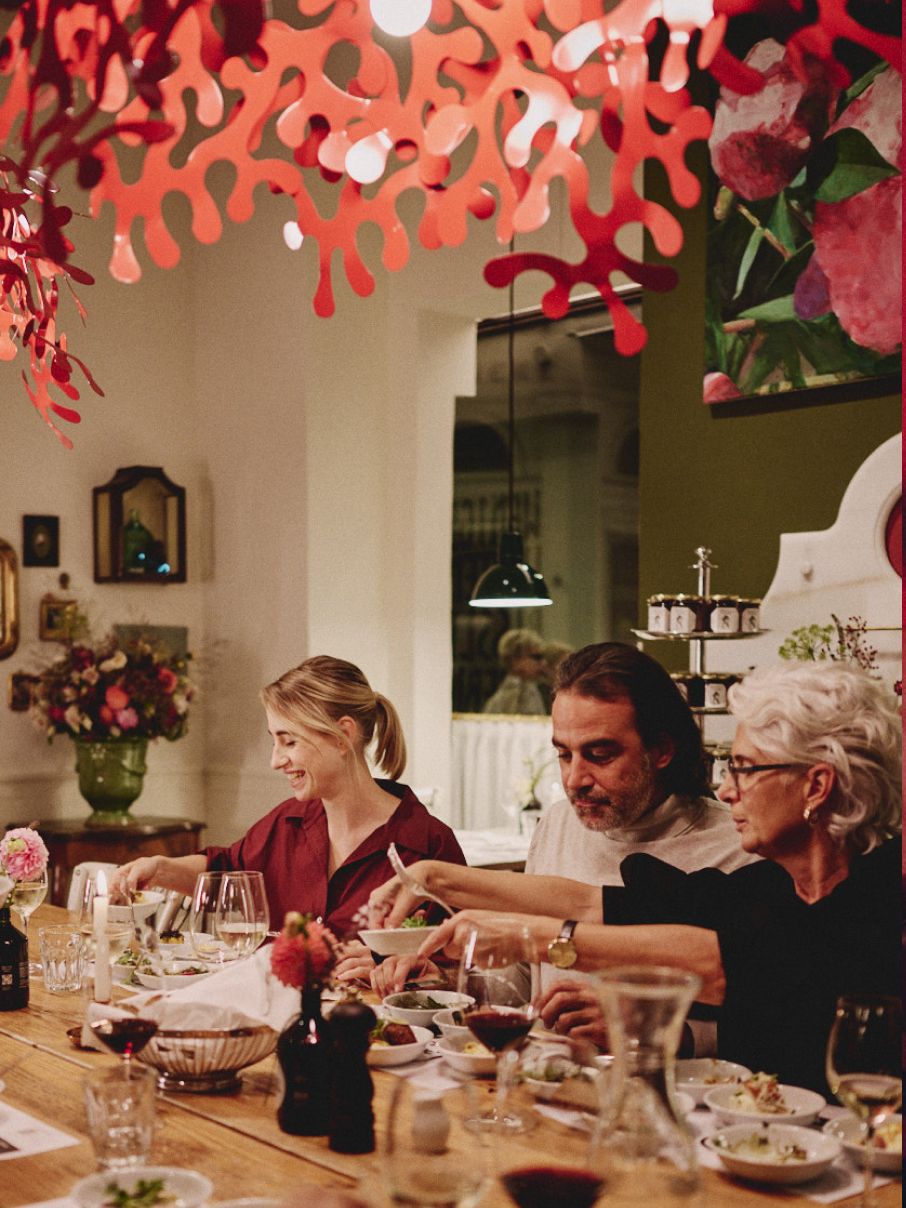 Menschen essen bei einer intimen, eleganten Veranstaltung zu Abend, mit roter Dekoration.