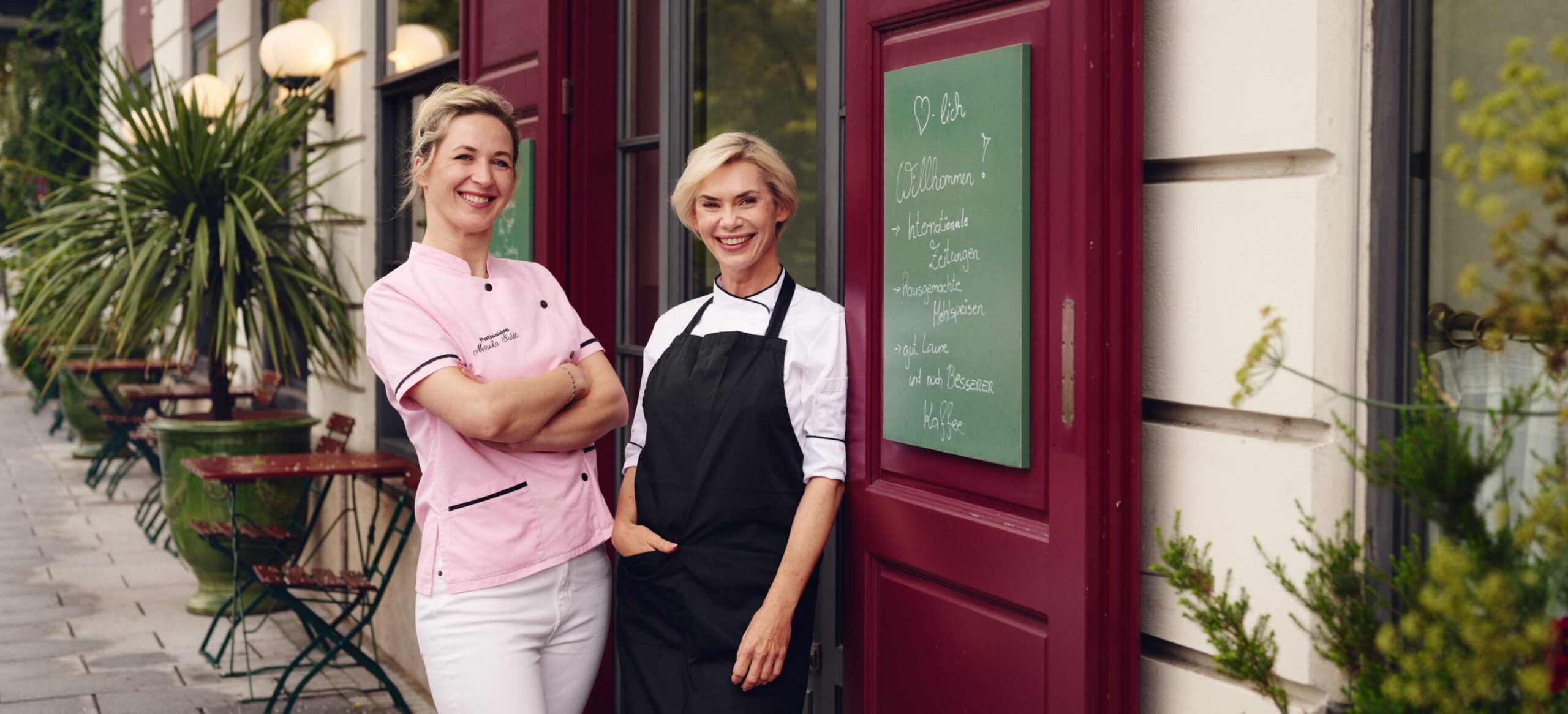 Zwei Frauen vor dem "O-Lish!" Restaurant mit Tafel und Speisekarte.