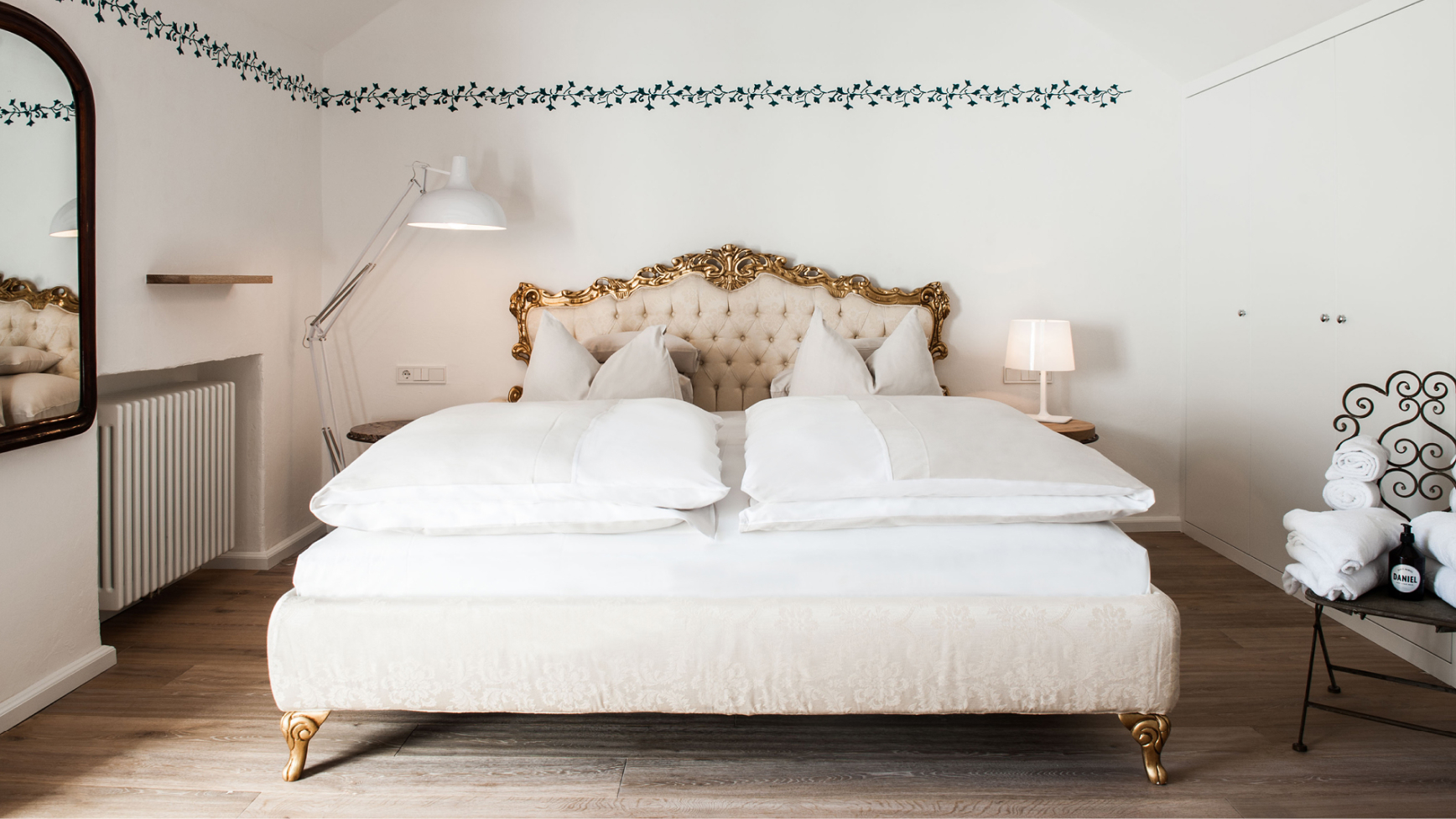 Ein Hotelzimmer mit weißer Bettwäsche, einem goldenen Bettrahmen und einer Lampe.