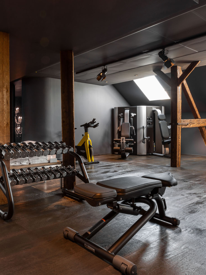 Ein Fitnessstudio mit Hanteln, einem gelben Trainingsfahrrad und verschiedenen Trainingsmaschinen.