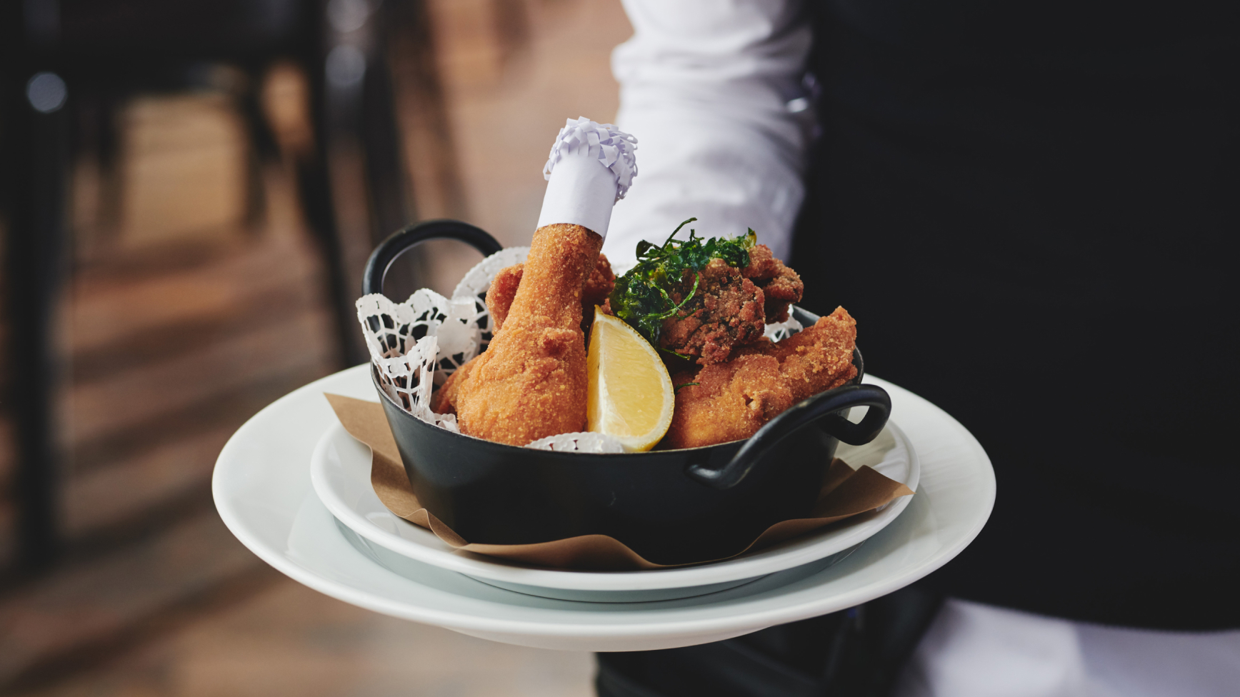 Frittiertes Huhn mit Zitrone, Kräutern und Kochmütze auf einem Serviertablett.