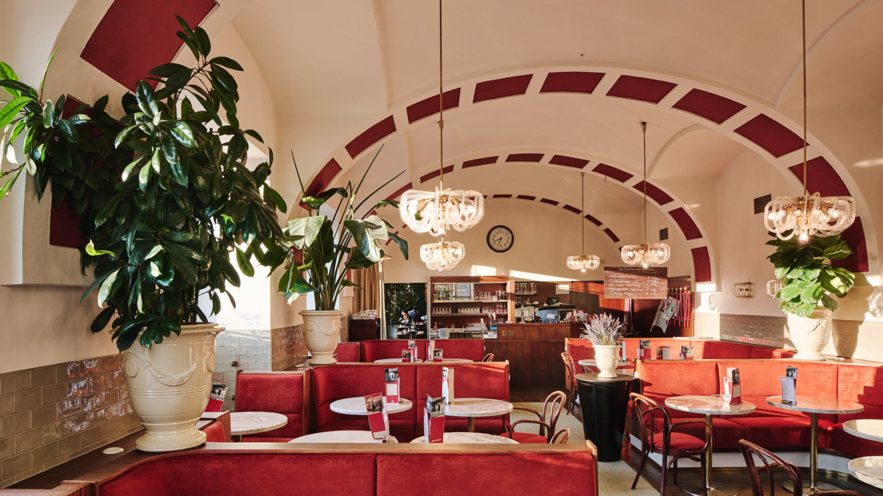Innenraum des Café Central in Wien mit roten Sitzen und Gewölbedecken.