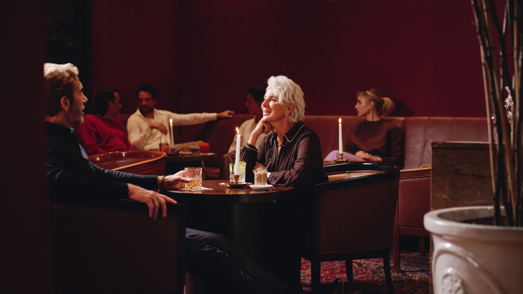 Innenraumaufnahme von Leuten, die in einer schummrigen Bar sitzen und Drinks an Tischen genießen.