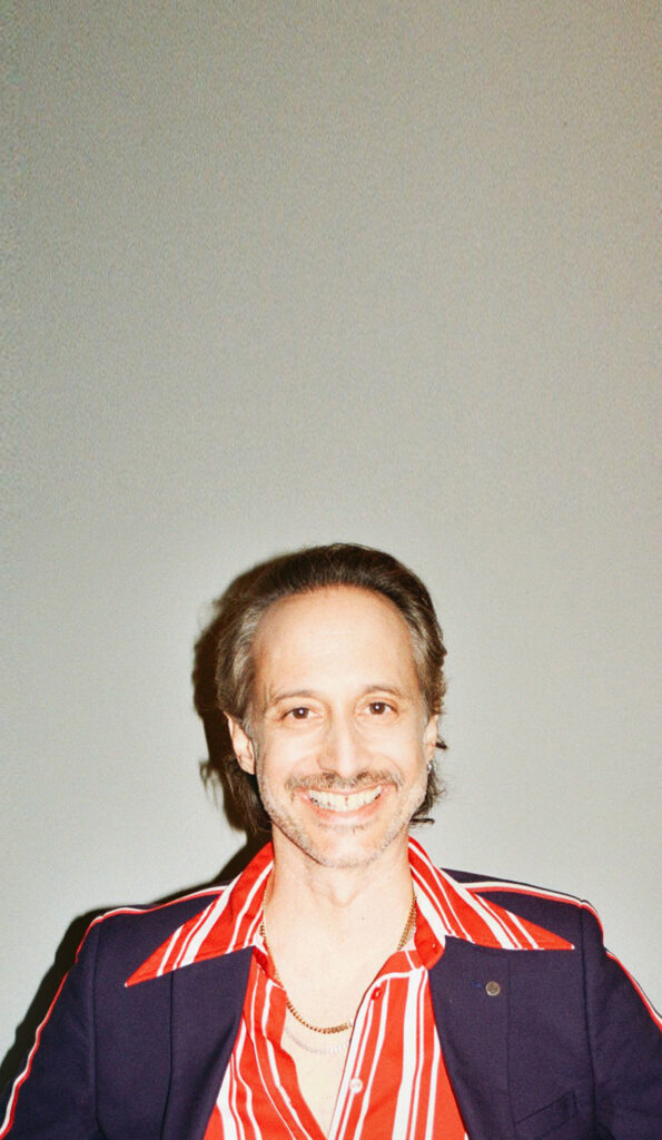 Michael Ostrowski lächelnd mit gestreiftem Hemd und dunkelblauem Sakko